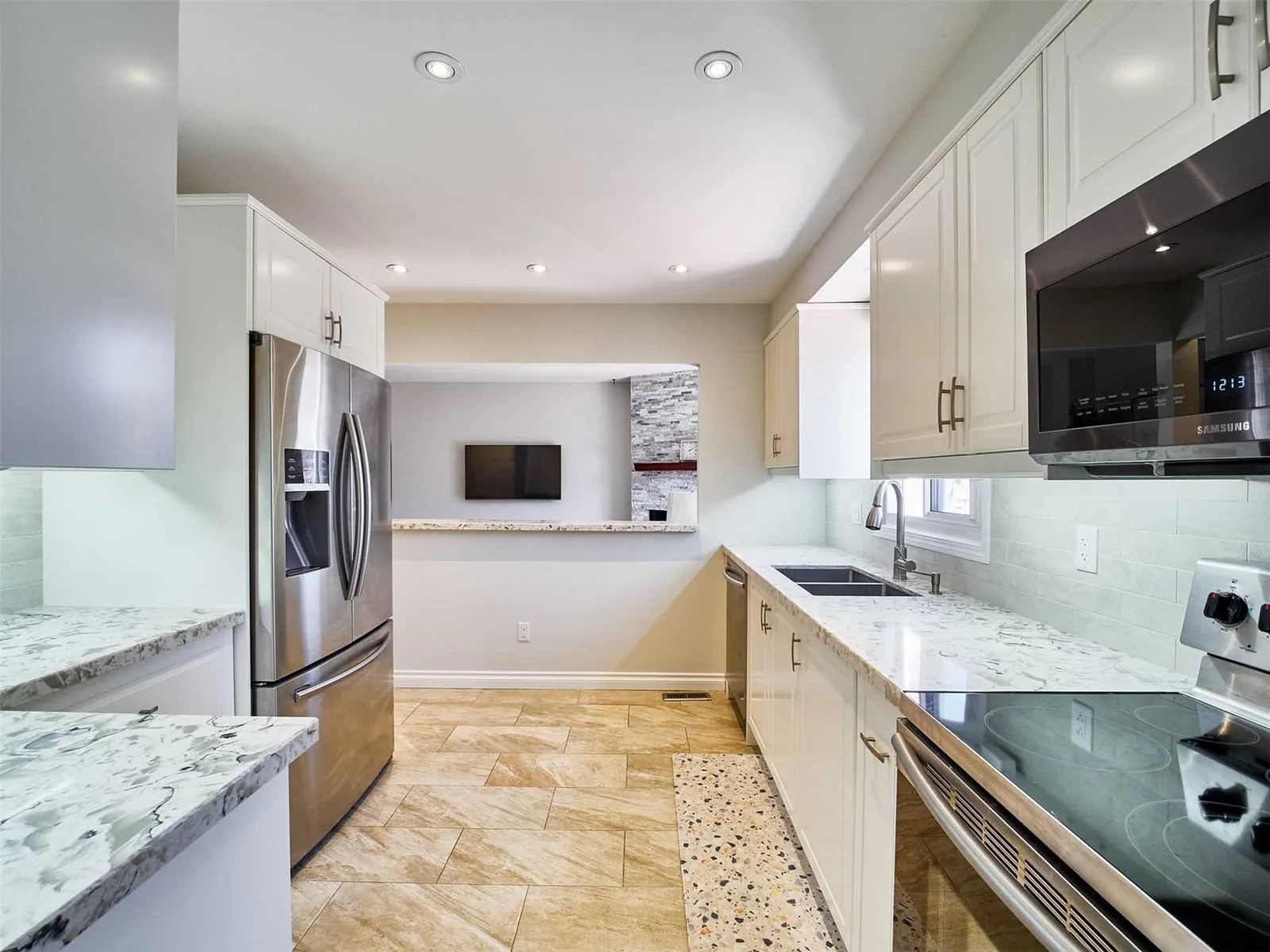 White galley kitchen with stone counters, stainless steel appliances and a pass-through to the family room